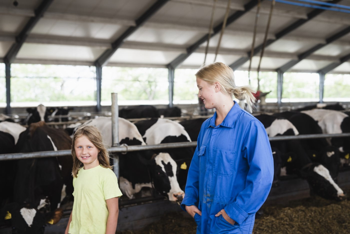 Mor og datter i fjøset og ser på kyr