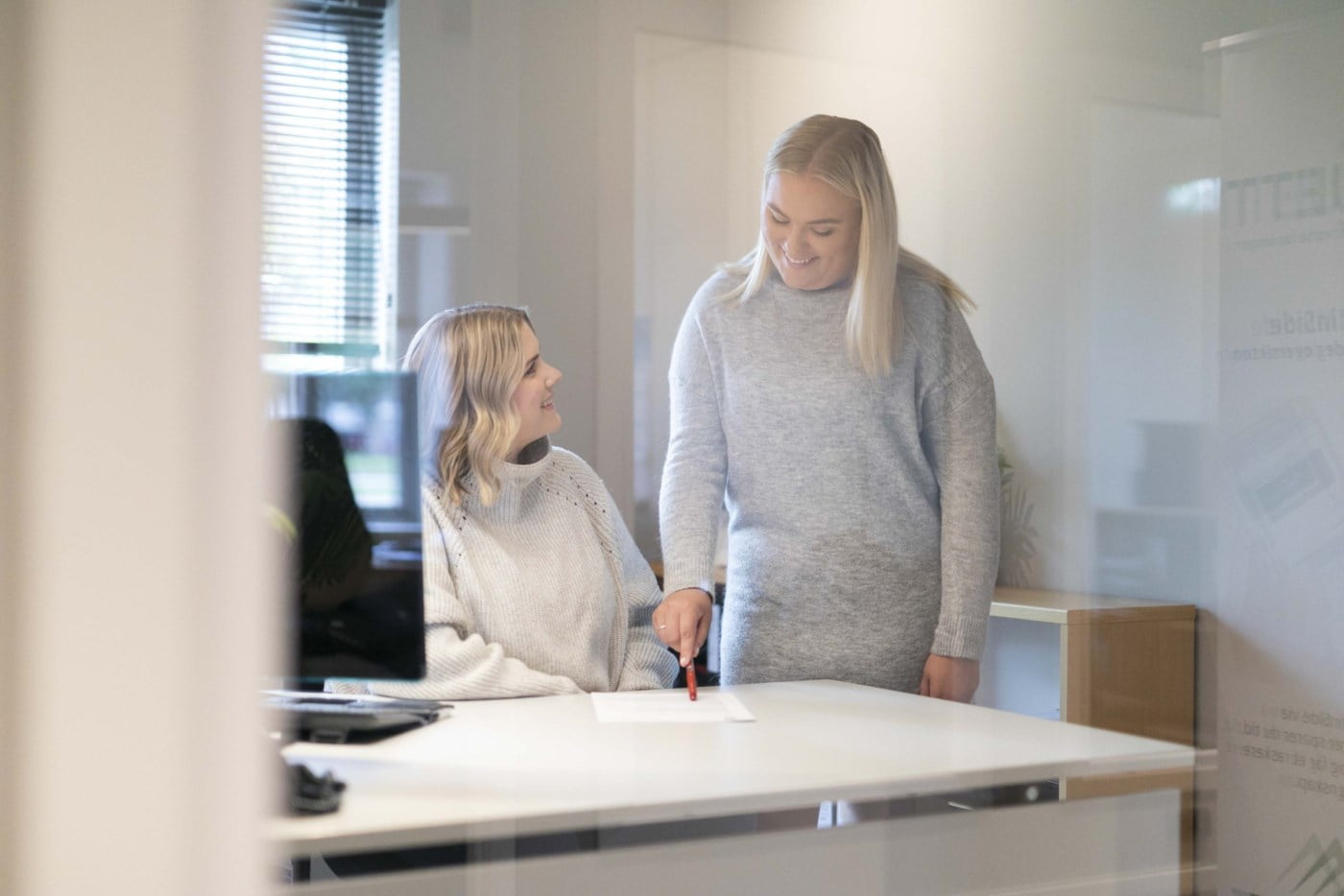 To ansatte som snakker sammen på et kontor