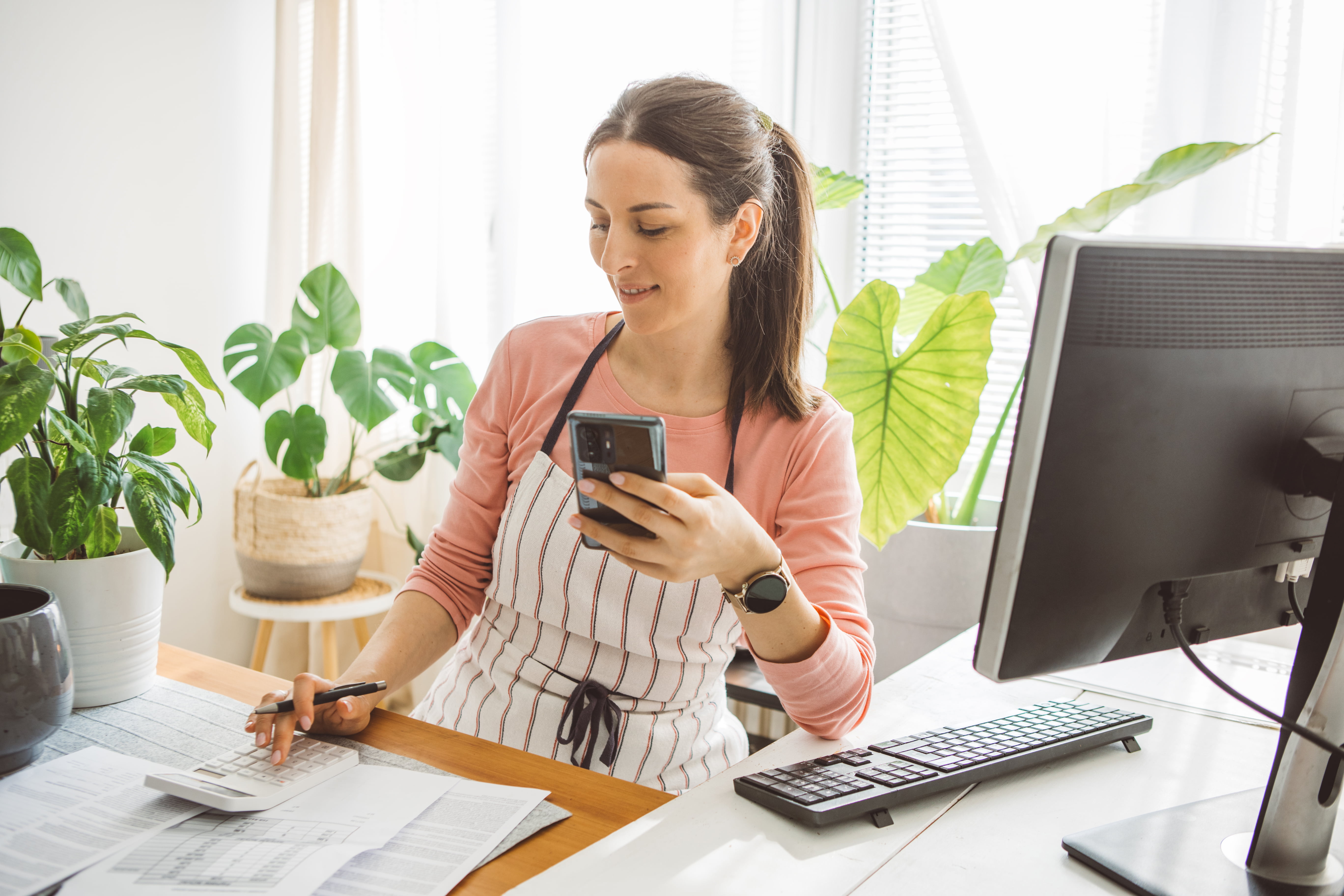 Dame som sitter med pc og kalkulator
