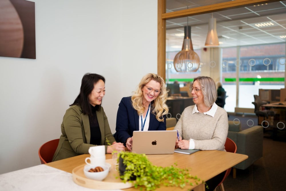 Tre ansatte som sitter på et kontor